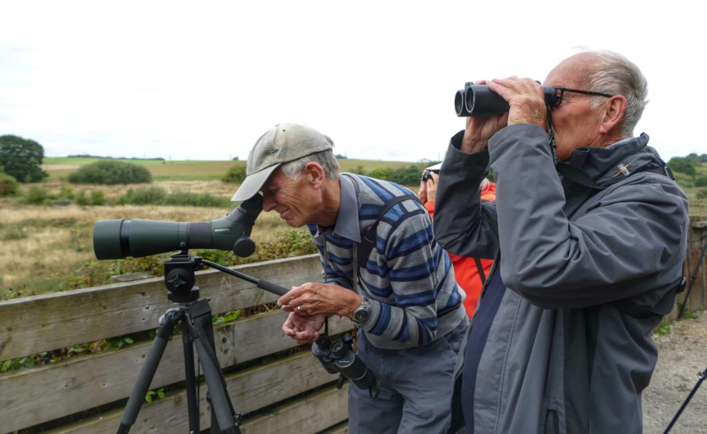 members searching with binoculars and a tripod